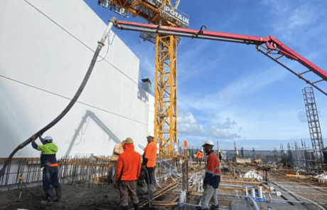 Construction workers on a high-rise site with a large crane featuring prominent signage.