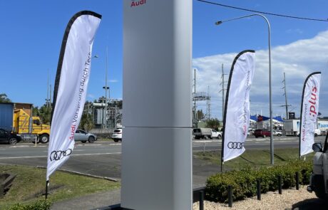 Tall Audi dealership pylon sign with branding and flags.