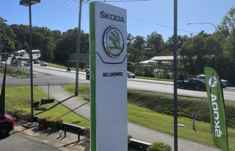 Workers installing a ŠKODA pylon sign at a dealership.