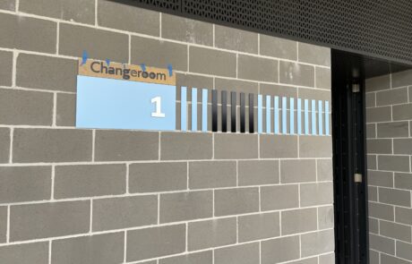 Directional wayfinding signage for sports facility changeroom.