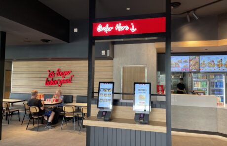 Interior digital menu and self-service kiosks at a KFC restaurant.