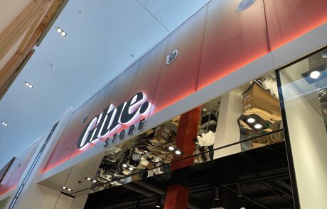 Illuminated storefront signage for Glue Store in a shopping mall.