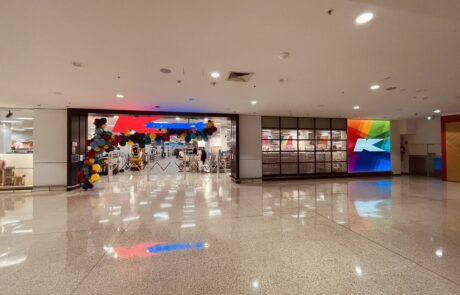 Kmart storefront entrance with colorful signage and balloon decorations.
