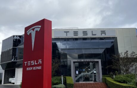 Tesla Body Repair red pylon sign with sleek branding.