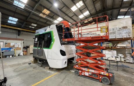 Metro train undergoing branding and wrap installation inside a workshop.