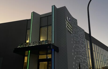 Arts centre entrance at dusk with LED vertical lighting and signage.