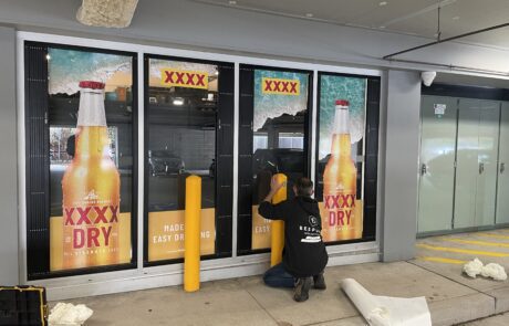Installation of XXXX Dry advertising vinyl wrap on store windows