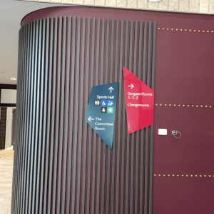 Modern wayfinding signage with bold geometric design, directing visitors inside a corporate or public building