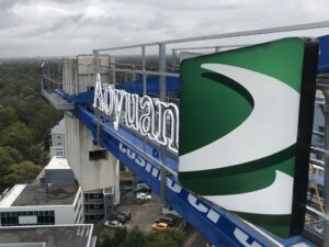 Large-scale illuminated sign being installed on a high-rise building using a crane for commercial branding