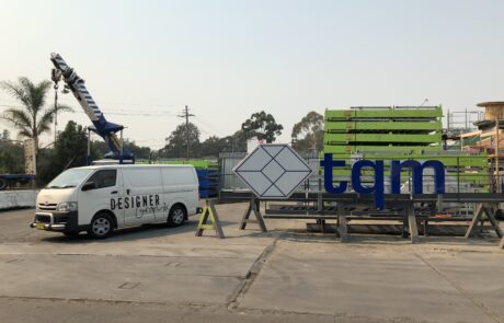 TQM signage being prepared for installation at an industrial site.
